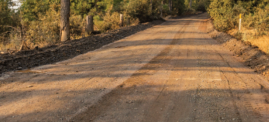 Carretera tratada con Dirt Perma-Zyme con puesta de sol proyectando sombras