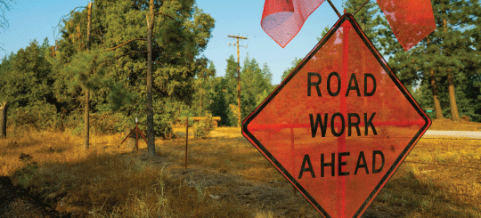 Señal naranja de obras por delante junto a una carretera sin pavimentar en California
